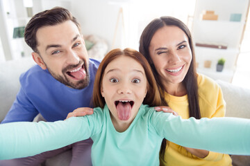 Photo of young family mom dad kid happy positive smile have fun fooling grimace tongue-out make selfie indoors - obrazy, fototapety, plakaty