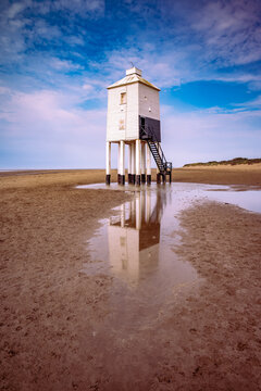 One of Three low lighthouses in the UK. This example is located at Burham on Sea. Standing tall at low tide with its reflection in a pool of sea water.