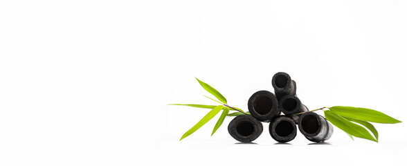 Bamboo activated charcoal sticks and green leaf isolated on white background.