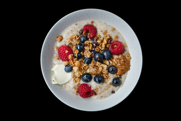 Top view of healthy cereal and oatmeal breakfast with berries and nuts in a white bowl. Ideal for...