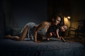 Mom holds the child by the scruff of the dress in her teeth in the nursery on the bed