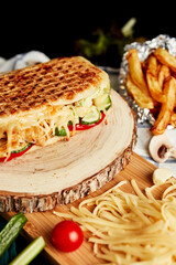 closed pizza on a wooden board with grated cheese and vegetables