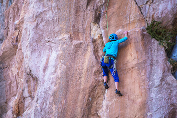 Obraz premium A woman in a helmet climbs a beautiful blue rock.