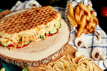 closed pizza on a wooden board with grated cheese and vegetables