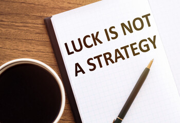 LUCK IS NOT A STRATEGY - text on notepad on wooden desk.