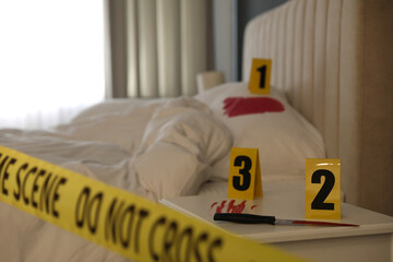 Bloody knife and crime scene markers on nightstand in bedroom