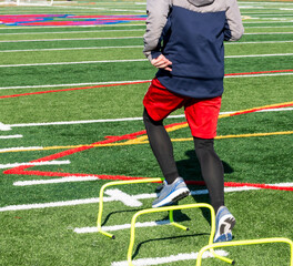 Runner running over yellow mini hurdles