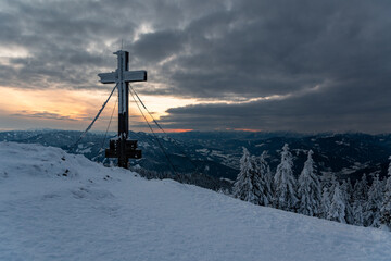 summit cross at "Rennfeld" mountain near the city Bruck an der Mur in Styria, Austria at sunset in winter