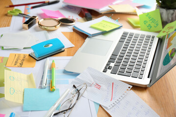 Messy table with laptop and stationery. Concept of being overwhelmed by work