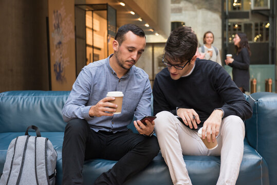 Students on coffee break, looking at phone