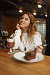 Relaxed woman eating cake and drinking cocoa