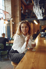 Attractive woman drinking tasty cocoa from straw at cafe