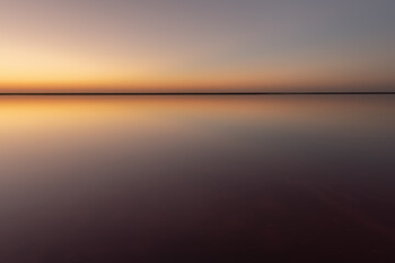 Tranquil minimalist landscape with smooth surface of the pink salt lake with calm water with...