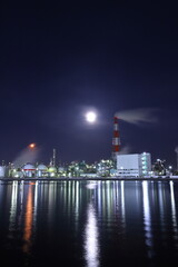 明るい月と水辺にある工場