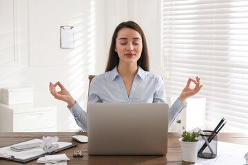 Businesswoman meditating at workplace in office. Stress relieving exercise