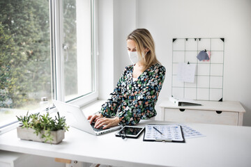 Businesswoman with ffp2 mask working at standing workstation in office