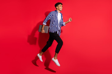 Fototapeta na wymiar Full length body size view of attractive cheerful skinny guy jumping running carrying laptop isolated on bright red color background