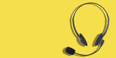 Headphones with a microphone on a yellow background. Panoramic image with place for your text.