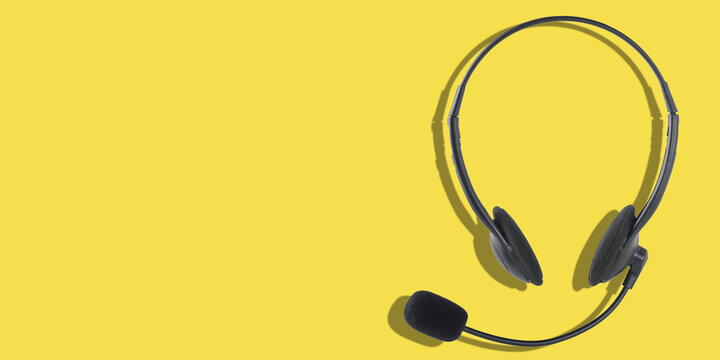 Headphones with a microphone on a yellow background. Panoramic image with place for your text.