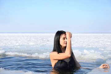 Woman immersing in icy water on winter day. Baptism ritual