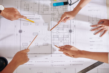 Hands of architects and designers pointing at blueprint on table when discussing future interior...