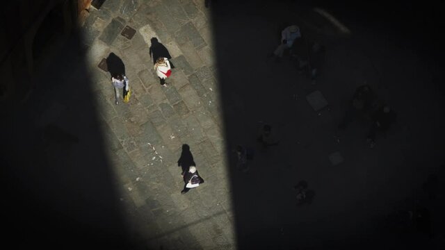 ray of sunshine between the towers of Bologna hits a lady who is waiting for someone