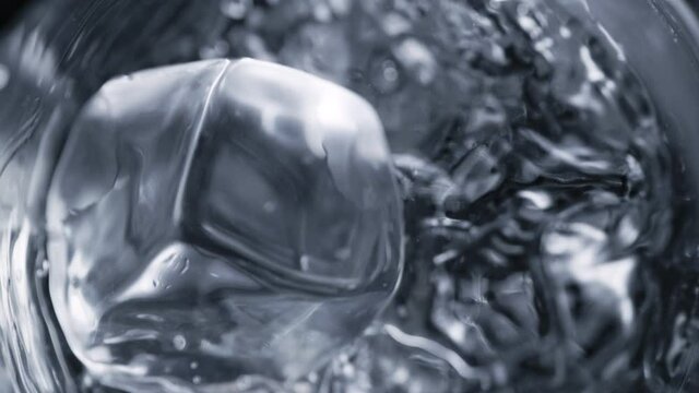 Super Slow Motion Detail Shot of Ice Cube Falling into Glass With Alcohol Liquid at 1000 fps.