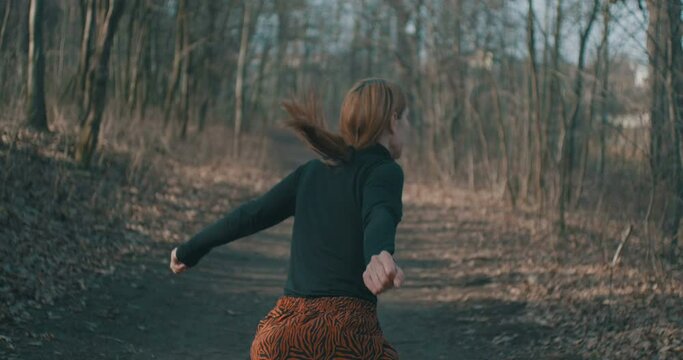 Joyfull woman is dancing in the forest.