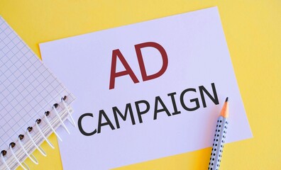 Ad Campaign text written on white paper above yellow background.Concept of an organized program of advertisements