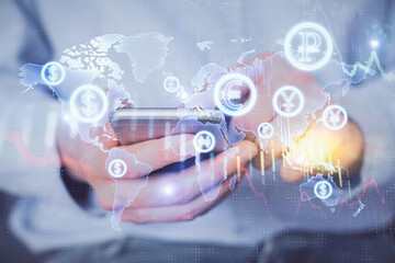 Double exposure of man's hands holding and using a digital device and forex graph drawing. Financial market concept.