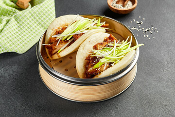 Bao bun with hoisin chicken. Bamboo steamer on dark slate table. Chinese, asian, authentic food...