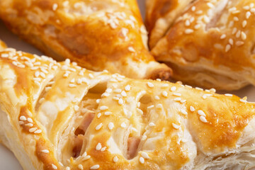 Delicious crunchy puffs with sesame seeds, ham and cheese. Delicious food, background. Yeast dough