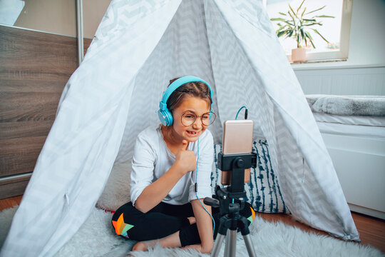 Little girl using a cellphone in her room in a tent.