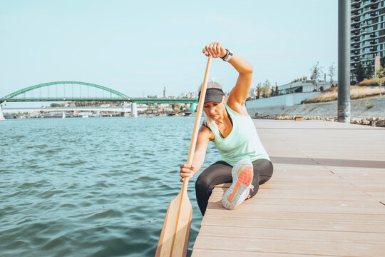 Woman in sportswear doing exercises near the river. Healthy lifestyle concept.