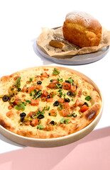 Olives and TOmato Focaccia and Cornbread on white table. White table and pink wall in sunlight with hard shadow. Summer day food concept.