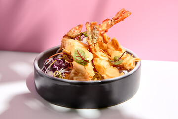 Restaurant seafood - Tempura shrimp & almond and cabbage salad. Appetizer food plate on white table with pink wall. Day sunlight with hard shadow of monstera palm leaves. Summer, spring food concept.
