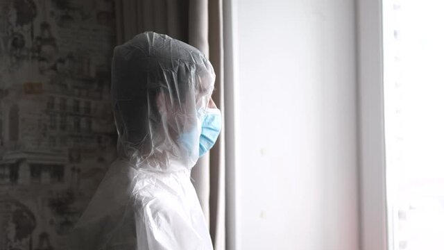 Portrait of a man wearing protective clothing with mask looking at window