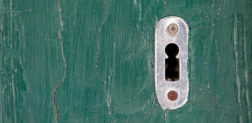 Keyhole detail with old green wooden door.