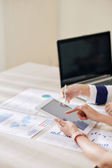 Close-up image of business people analyzing statistics on tablet computer showing results of their successful work
