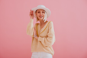 Happy smiling woman wearing trendy yellow sweater, stylish silver wrist watch, white hat posing on...