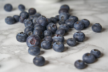 A group of fresh blueberries on a white and black marble table. 