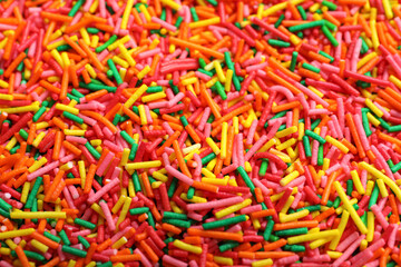 Bright colorful sprinkles as background, closeup. Confectionery decor