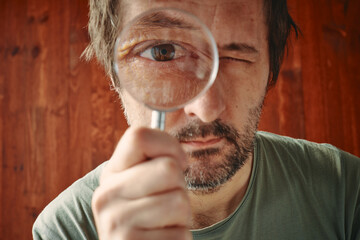 Curious man looking through magnifying glass