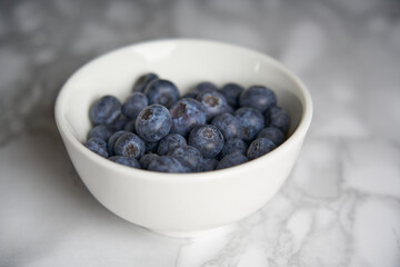 A group of fresh blueberries on a white and black marble table. 