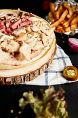 closed pizza on a round wooden board on a black background