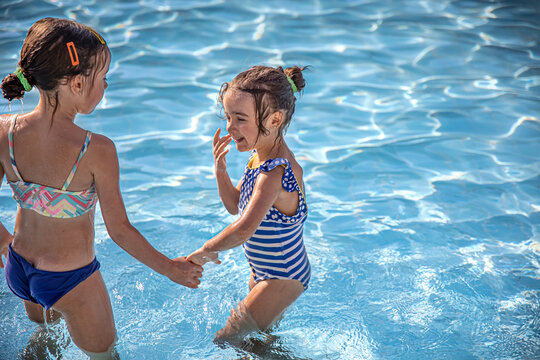 Two little girls swim in the pool copy space.