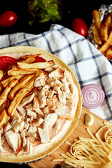 closed pizza on a round wooden board on a black background