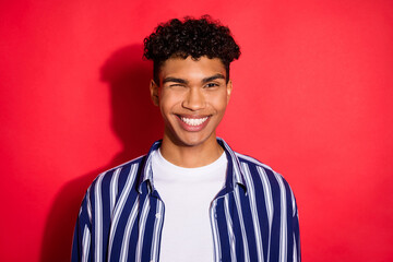 Photo of young handsome african man happy positive smile blink eye isolated over red color background