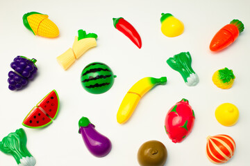 Creative pattern of toy fruits and vegetables on a white background. Minimal food concept.