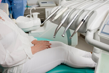 Fototapeta premium woman sitting in dentist chair, with surgical material, dental hospital background